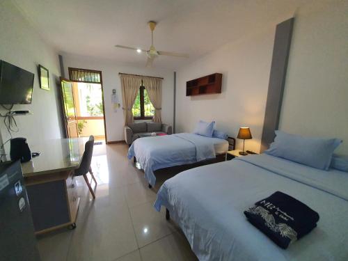 a hotel room with two beds and a couch at MB Apartments & Hotel Medan in Sunggal