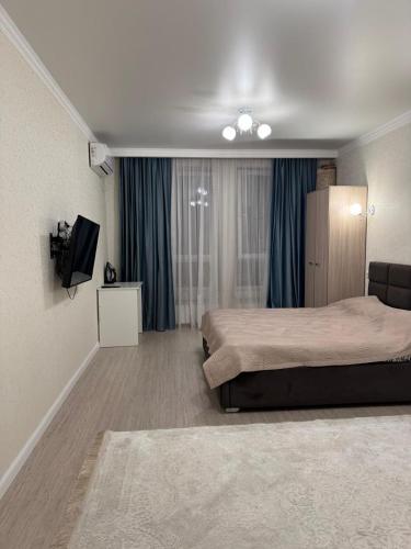 a hotel room with two beds and a flat screen tv at Жк Райымбек in Almaty