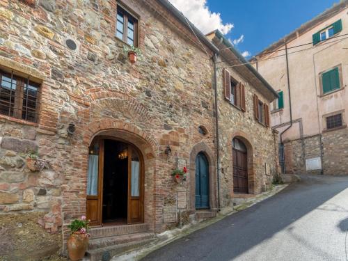 an old brick building with a door in a street at Holiday Home in Tuscany with Pool in Orciatico
