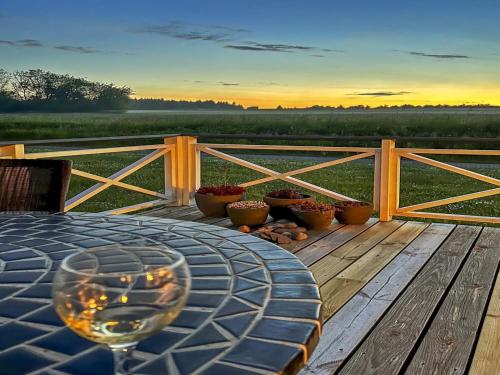 a table with a glass of wine on a wooden deck at Apartment Helemine - 2-8km from the sea by Interhome in Gudhjem