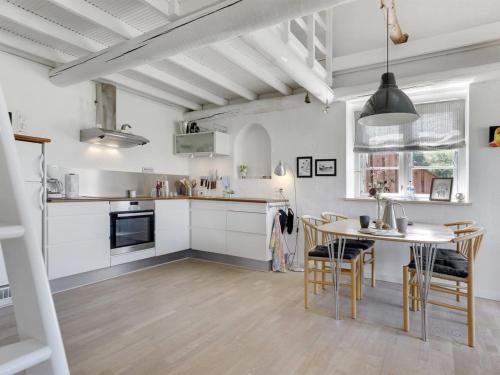 a kitchen with white cabinets and a table and chairs at Apartment Antine - 6km from the sea by Interhome in Åkirkeby