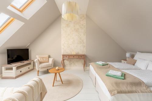 a bedroom with a bed and a tv and a couch at Herczeg-Fekete Cottage Birtokközpont in Simontornya