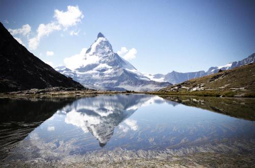 a mountain with its reflection in a body of water at CAYA Bijou im Herzen von Zermatt in Zermatt