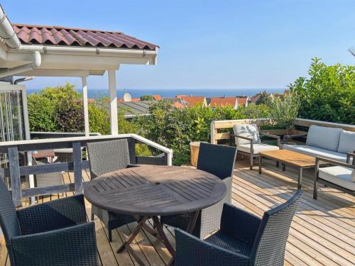 a wooden deck with a table and chairs on a balcony at Holiday Home Jolanda - 800m from the sea by Interhome in Gudhjem