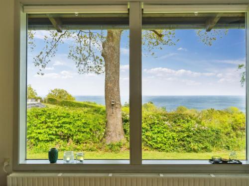 a window with a view of a tree and the ocean at Holiday Home Esben - 350m from the sea by Interhome in Allinge