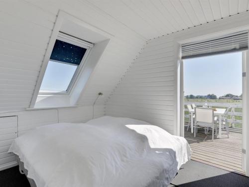 a white bedroom with a bed and a balcony at Holiday Home Nilia - 3-5km from the sea by Interhome in Østermarie