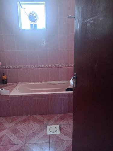 ein rosafarbenes Badezimmer mit Badewanne und Fenster in der Unterkunft Sky apartment in Amman