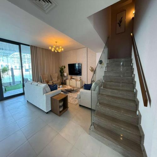 a living room with a staircase and a couch and a television at Luxury 5BR Villa Private Pool & Beach Access in Sharjah