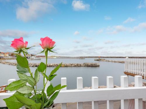 a white fence with a pink flower next to the water at Holiday Home Fridhild - 10m from the sea by Interhome in Hasle
