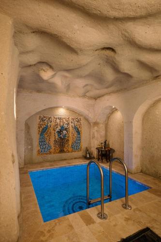 a swimming pool in a stone room with a blue swimming poolvisor at Cappadocia Cave Suites Adult Only in Goreme
