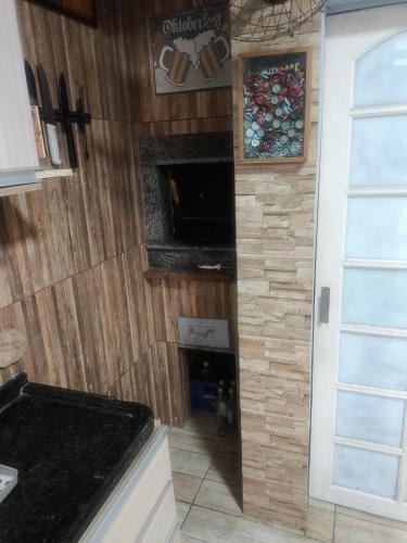 a kitchen with wooden walls and a fireplace at Casa locação centro Navegantes in Navegantes