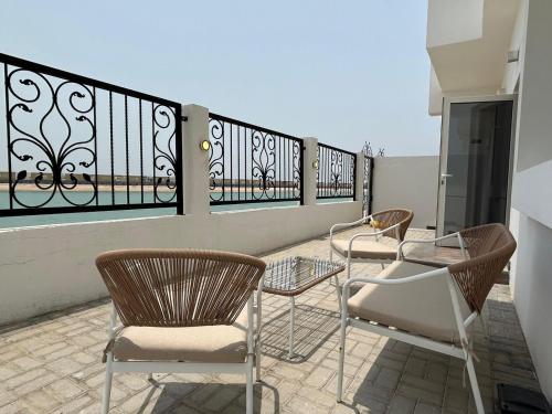 a patio with chairs and tables on a balcony at Beach Front 03 bedroom villa plus maid room in Al Ḩamrīyah
