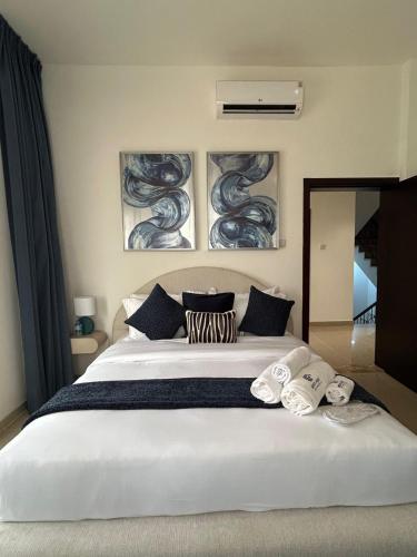 a bedroom with a large white bed with three paintings on the wall at Beach Front 03 bedroom villa plus maid room in Al Ḩamrīyah