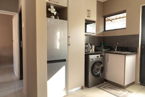 una cocina con nevera y lavadora en Matusadona Suites, en Mokopane