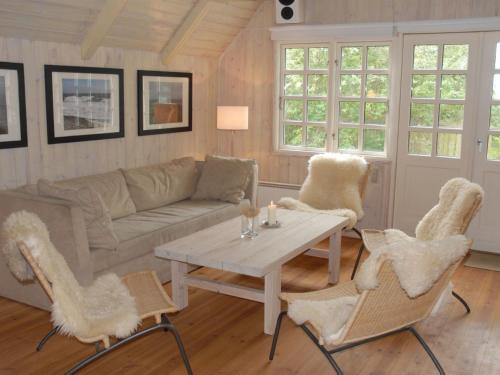 a living room with a couch and a table and chairs at Holiday Home Kalv - 75m from the sea by Interhome in Østerby