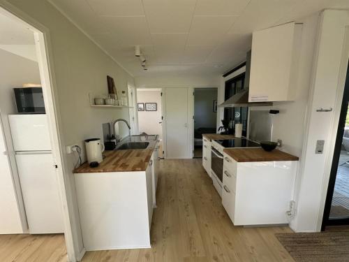 a kitchen with white cabinets and a wooden floor at Holiday Home Ady - 150m from the sea by Interhome in Augustenborg