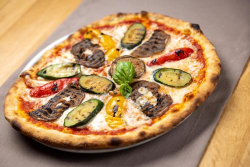 a pizza sitting on a plate on a table at Hotel Sonne St. Moritz 3* Superior in St. Moritz