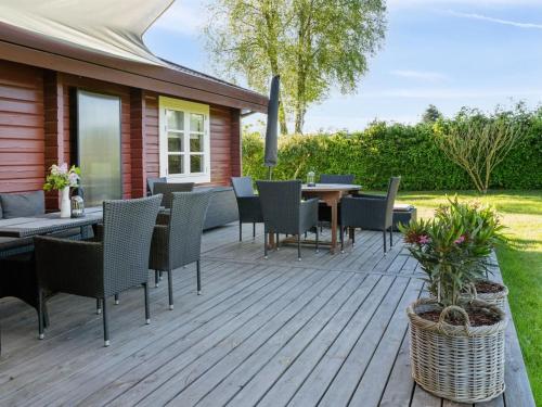 eine Holzterrasse mit einem Tisch und Stühlen darauf in der Unterkunft Holiday Home Swartebrand - 450m from the sea by Interhome in Neder Lysabild