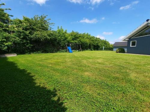 a large grassy yard with a blue playground at Holiday Home Toja - 700m from the sea by Interhome in Neder Lysabild