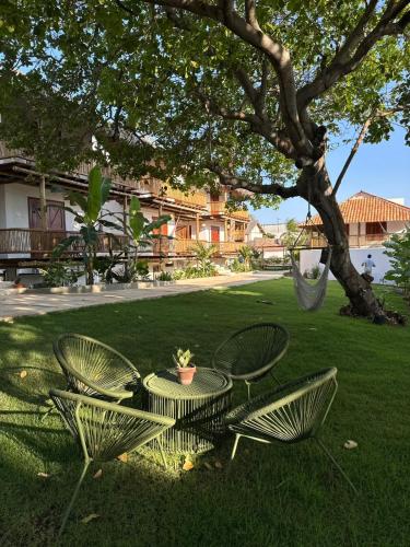 a table and chairs sitting in the grass under a tree at Pousada Villa Tibá in Jericoacoara