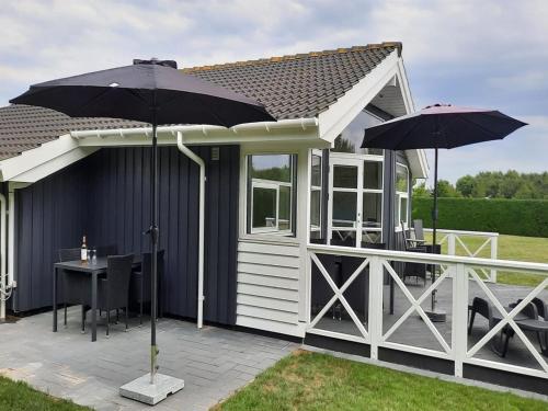 a cabin with a table and an umbrella at Holiday Home Gustava - 700m from the sea by Interhome in Neder Lysabild