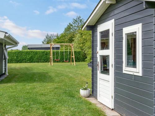 a yard with a playground next to a house at Holiday Home Gustava - 700m from the sea by Interhome in Neder Lysabild