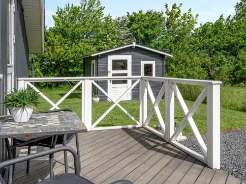a wooden deck with a fence and a cabin at Holiday Home Gustava - 700m from the sea by Interhome in Neder Lysabild