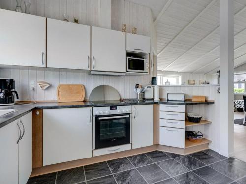 a kitchen with white cabinets and a stove at Holiday Home Gustava - 700m from the sea by Interhome in Neder Lysabild