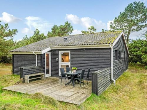 a tiny house with a deck and a table at Holiday Home Samuli - 400m from the sea by Interhome in Fanø