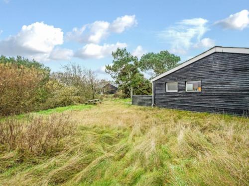 a black house on a grassy hill next to a building at Holiday Home Samuli - 400m from the sea by Interhome in Fanø
