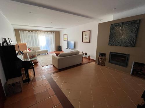 a living room with a couch and a fireplace at Vivenda espaçosa com jardim e churrasqueira in Alcabideche