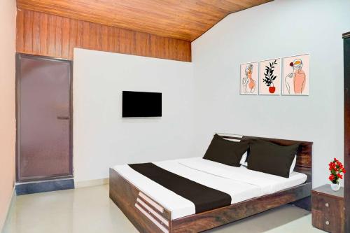 a bedroom with a bed and a tv on the wall at Collection O Malavli Lonavala Hill View in Lonavala