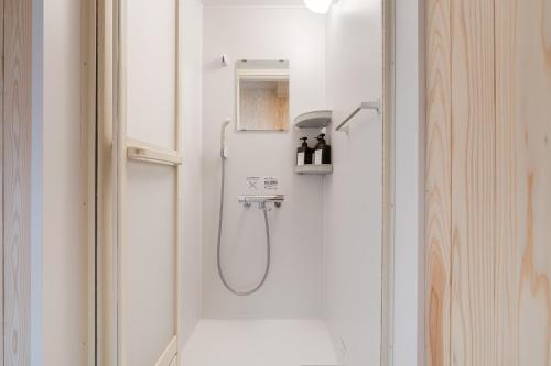 a shower in a white bathroom with a shower at Tokyo Manga Stay 駅1分貸切で85平米 日本の有名マンガが読める宿 9名までOK in Tokyo