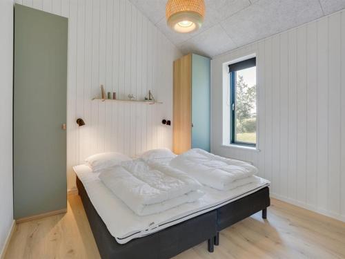 a bedroom with a bed with white sheets and a window at Holiday Home Gojana - 400m from the sea by Interhome in Nordborg