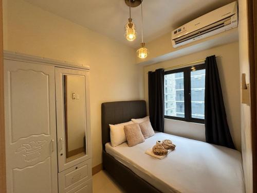a small bedroom with a bed with a window at Shore 3 Residences RM 674 Pool View by Prime Stay MOA in Sampong