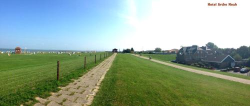 a grassy field with a fence and animals in the distance at NordseeResort Hotel & Suite Arche Noah in Horumersiel