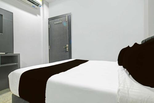 a bedroom with a white bed and a door at Hotel O Mahakal in Ujjain