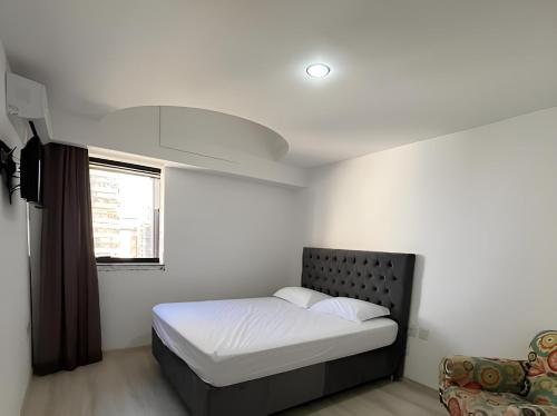 a small bedroom with a bed and a window at Sensacional Flat pé na areia na Praia da Costa in Vila Velha