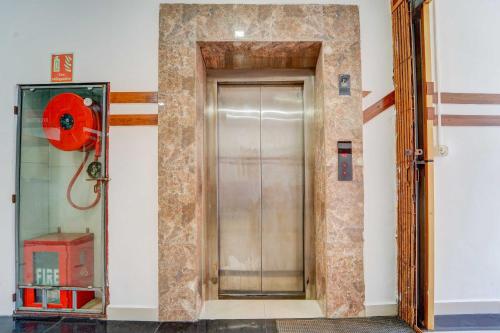 a glass elevator door in a room with a red fan at Collection O Kottayam Near Caritas Hospital in Kottayam