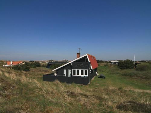 a black house with a red roof in a field at Holiday Home Casandra - 600m from the sea by Interhome in Fanø