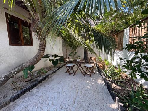 a patio with a table and chairs under a palm tree at Beach Bohème in Paje