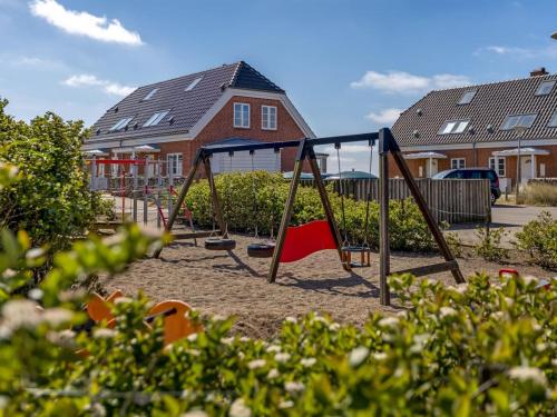 a playground with two swings in front of houses at Holiday Home Joonas - 100m from the sea by Interhome in Havneby