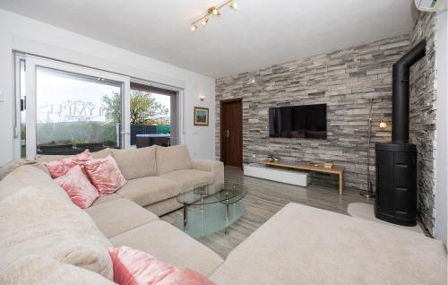 a living room with a couch and a stone wall at Cozy Home In Kastel Stafilic in Kaštela