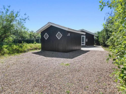 a black shed with a gravel driveway at Holiday Home Andine - 1-2km from the sea by Interhome in Fanø