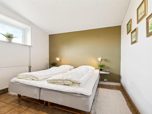 a bedroom with a bed with white sheets and a window at Holiday Home Kita - 500m from the sea by Interhome in Lakolk