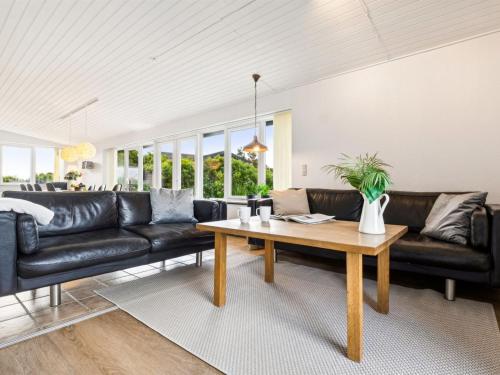 a living room with black leather couches and a table at Holiday Home Kita - 500m from the sea by Interhome in Lakolk