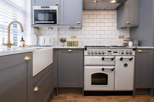 a kitchen with a white stove and a sink at Beautiful Mews Cottage near Brighton Seafront in Rottingdean Village in Rottingdean