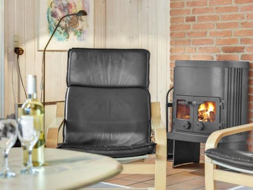 - un fauteuil en cuir devant une cheminée dans l'établissement Holiday Home Harthwik - 1km from the sea by Interhome, à Mølby