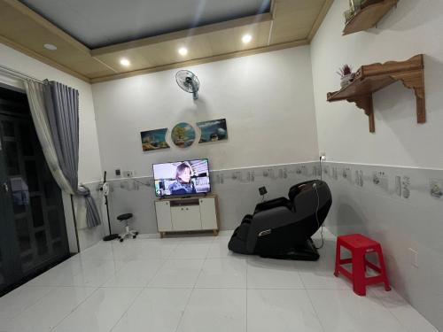 a living room with a tv and a red stool at The Milla Home Tà Lài-Đồng Nai in Tân Phú