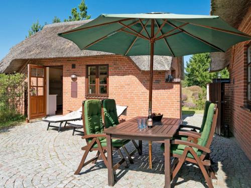 einen Holztisch und Stühle mit einem grünen Sonnenschirm in der Unterkunft Holiday Home Siegried - 2-2km from the sea by Interhome in Vesterhede